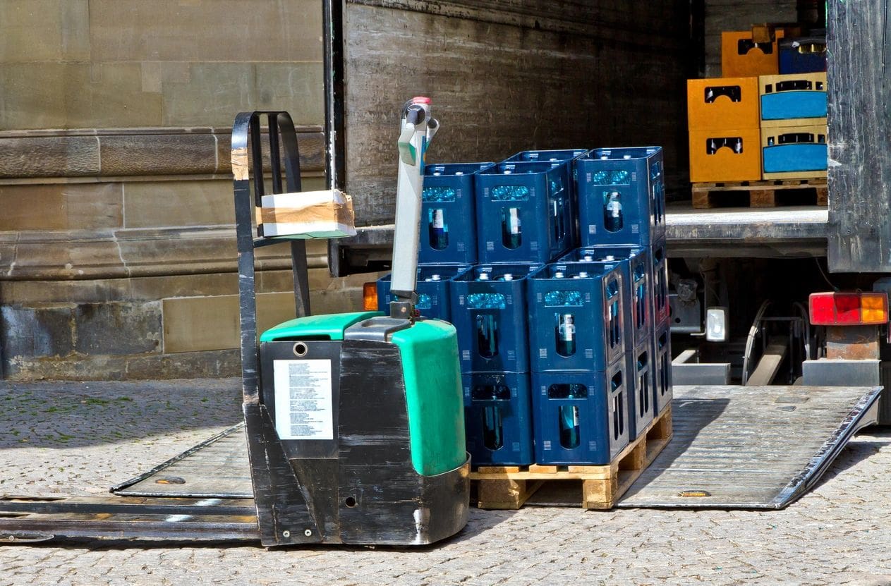 A pallet of water bottles sitting next to a forklift.