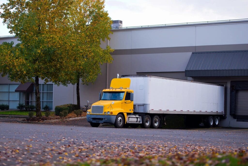 A yellow and white truck parked in front of a building.